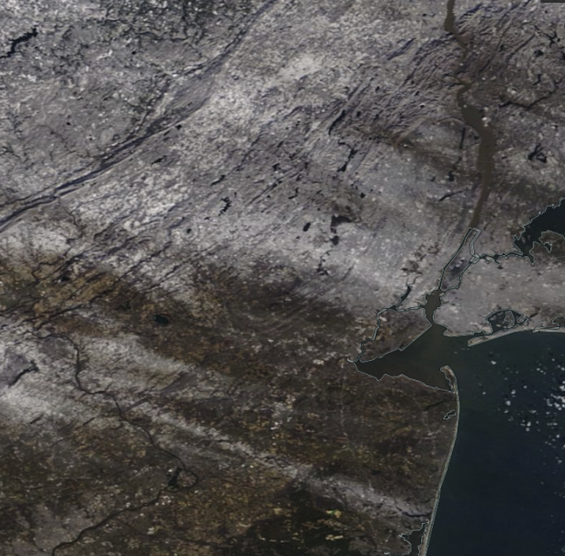 Figure 5. Snow cover across northern and central NJ and surrounding areas on the morning of December 19. Skies over the land are cloud-free, thus the streaks of white of various shades are snow that was laid down in squalls the previous afternoon and evening. Some snow cover toward the north also remains from snowfalls earlier in the month. (NASA MODIS image) NASA MODIS satellite image showing snow cover on December 19th